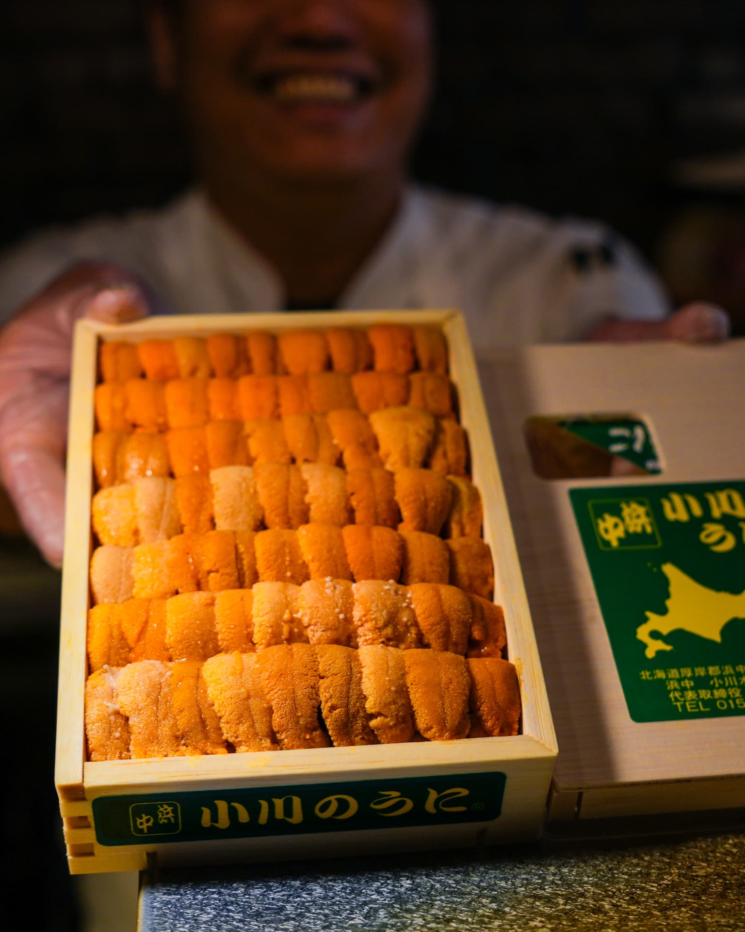 Chef presenting a wooden tray of Hokkaido uni